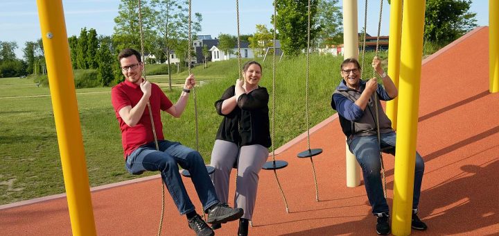 Eine Frau und zwei Männer sitzen auf einer Schaukel